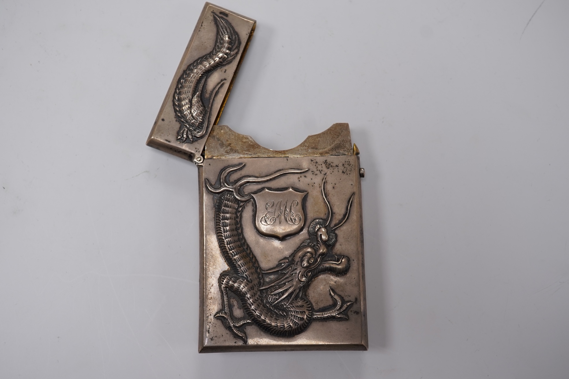 A late 19th century Chinese Export white metal card case, by Cum Shing, Canton, embossed with a dragon and applied shield shaped panel engraved with monogram, 90mm, 85 grams.